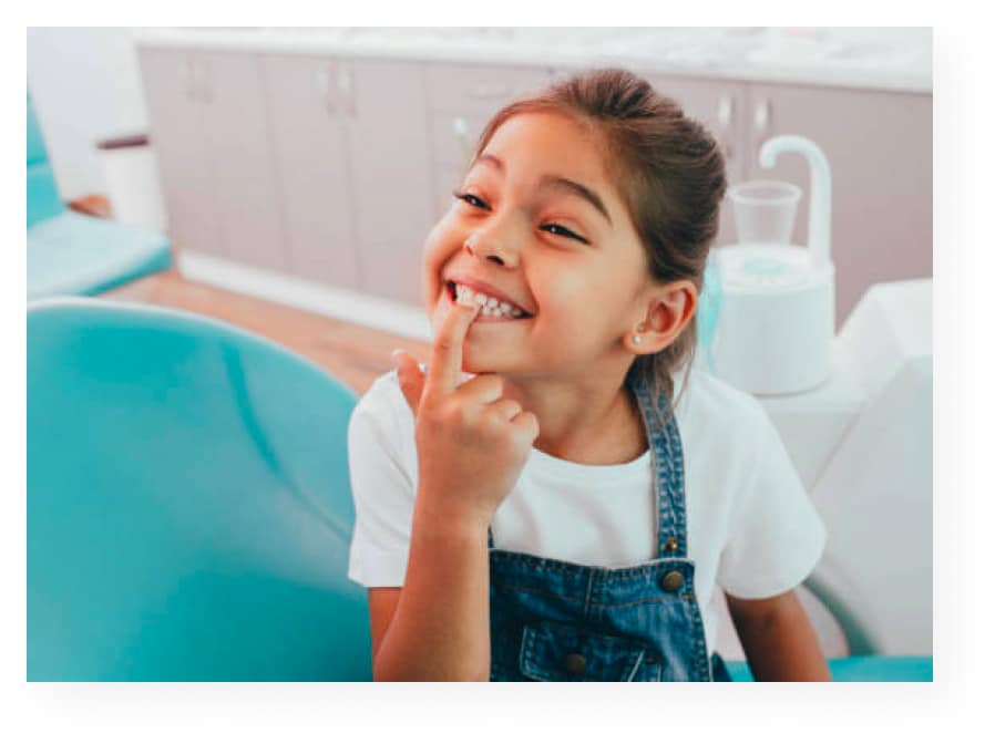 Young girl pointing to her teeth at dentist office.